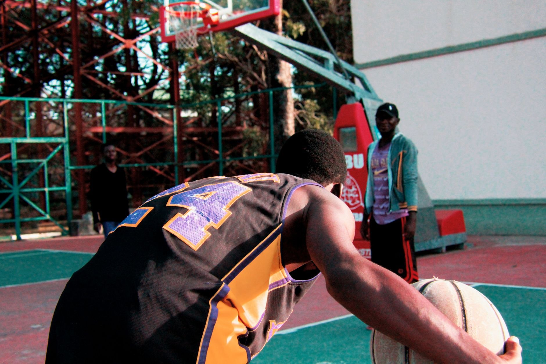 An energetic outdoor basketball game with players in action on a court during the day.